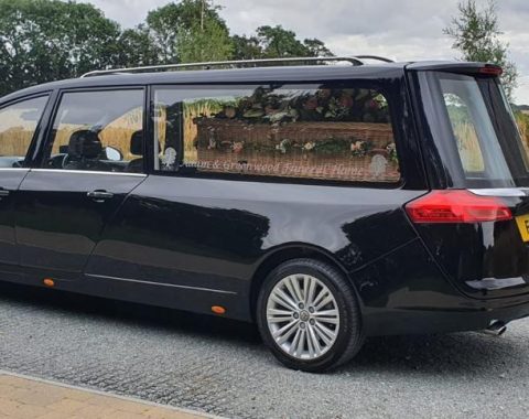 Traditional Services - Black hearse with a wicker coffin in